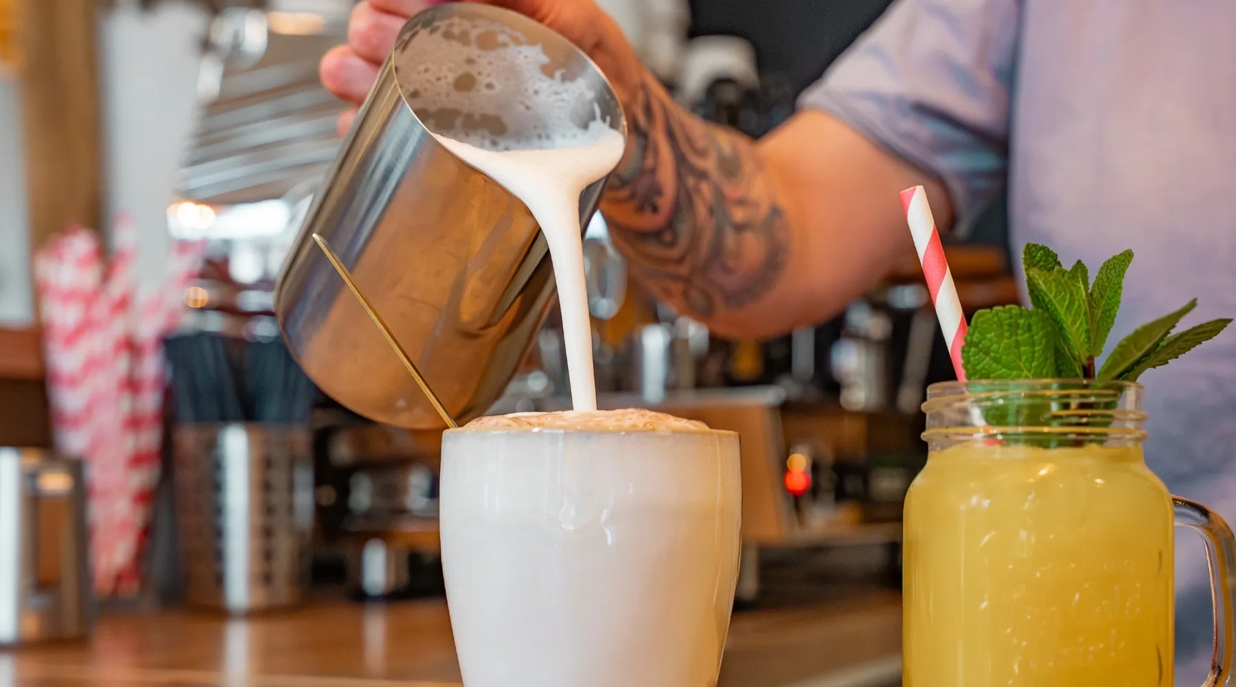 Barista gießt Milchschaum in eine Tasse Kaffee